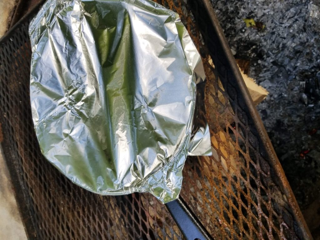 camping cooking on grate over fire 
