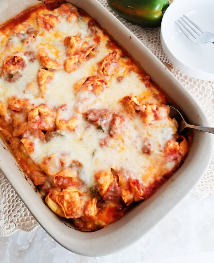 Italian Sausage & Tortellini Bake in baking dish with serving spoon 