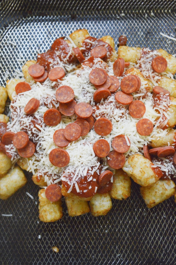 tator tots loaded with sauce, cheese, pepperoni on air fryer basket 
