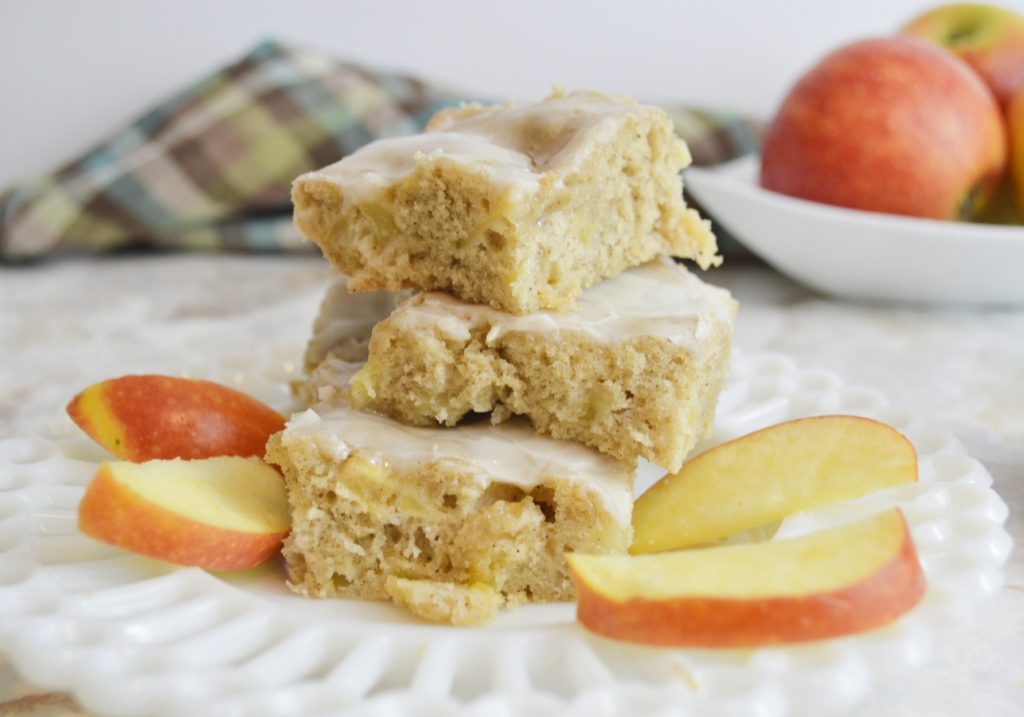 Apple blondies stacked on white plate with apple slices 