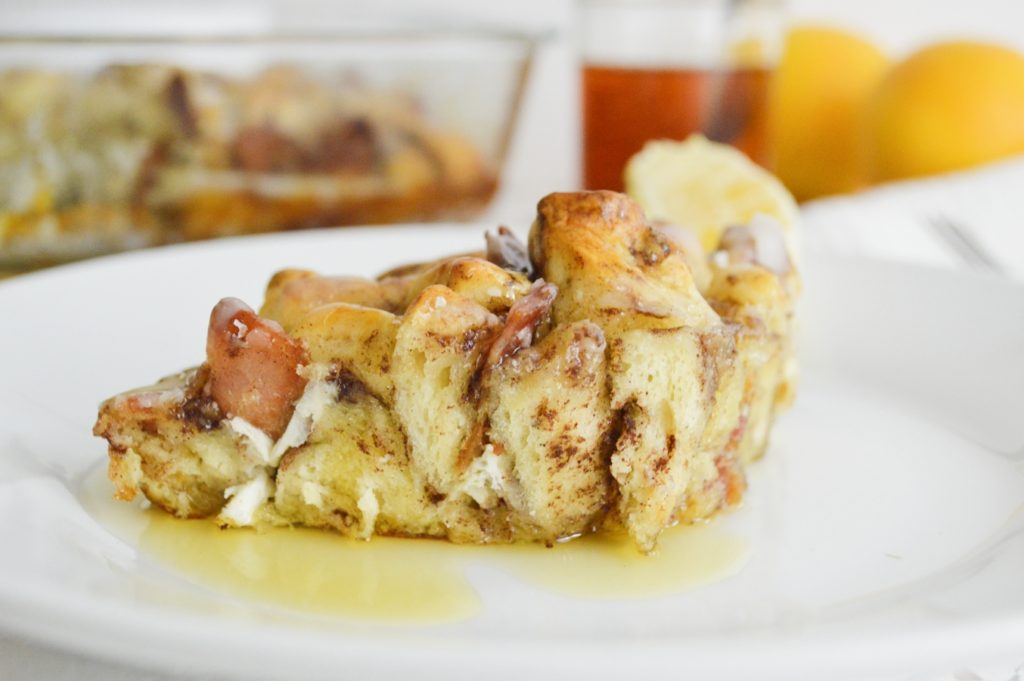 Close up of cinnamon roll french toast casserole slice on plate with syrup