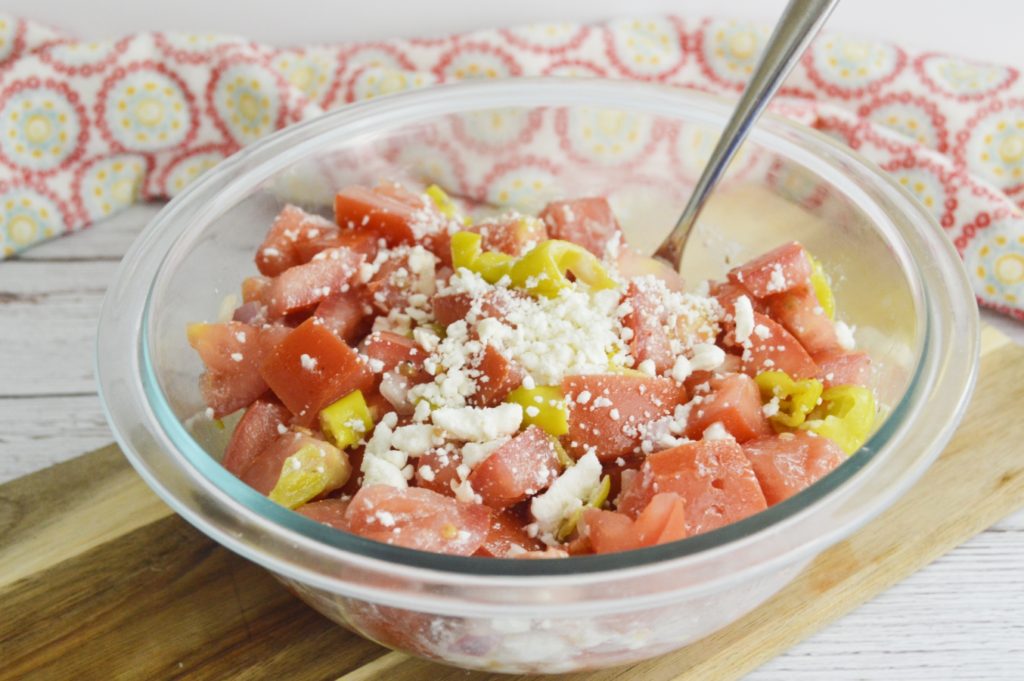 marinated tomato salad with feta in bowl with spoon 