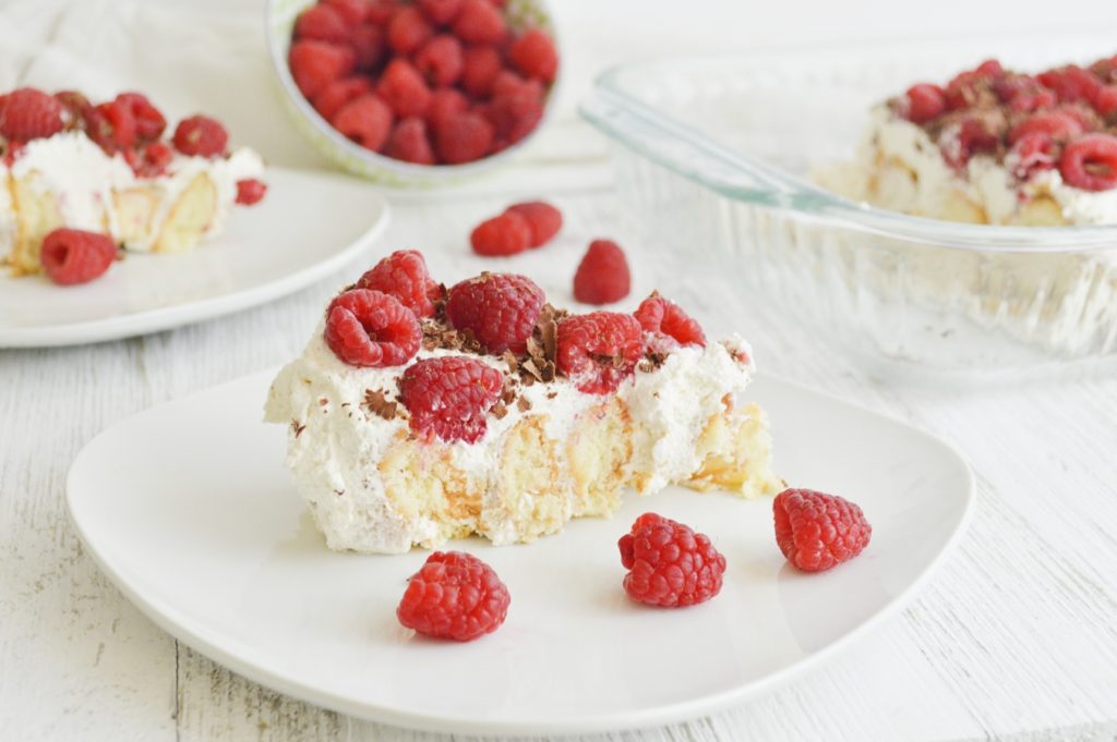 slice of simple raspberry icebox cake on white plate with raspberries