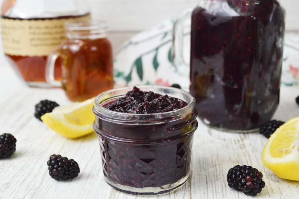 blackberry vanilla bourbon jam in jelly jars with blackberries and lemon wedges