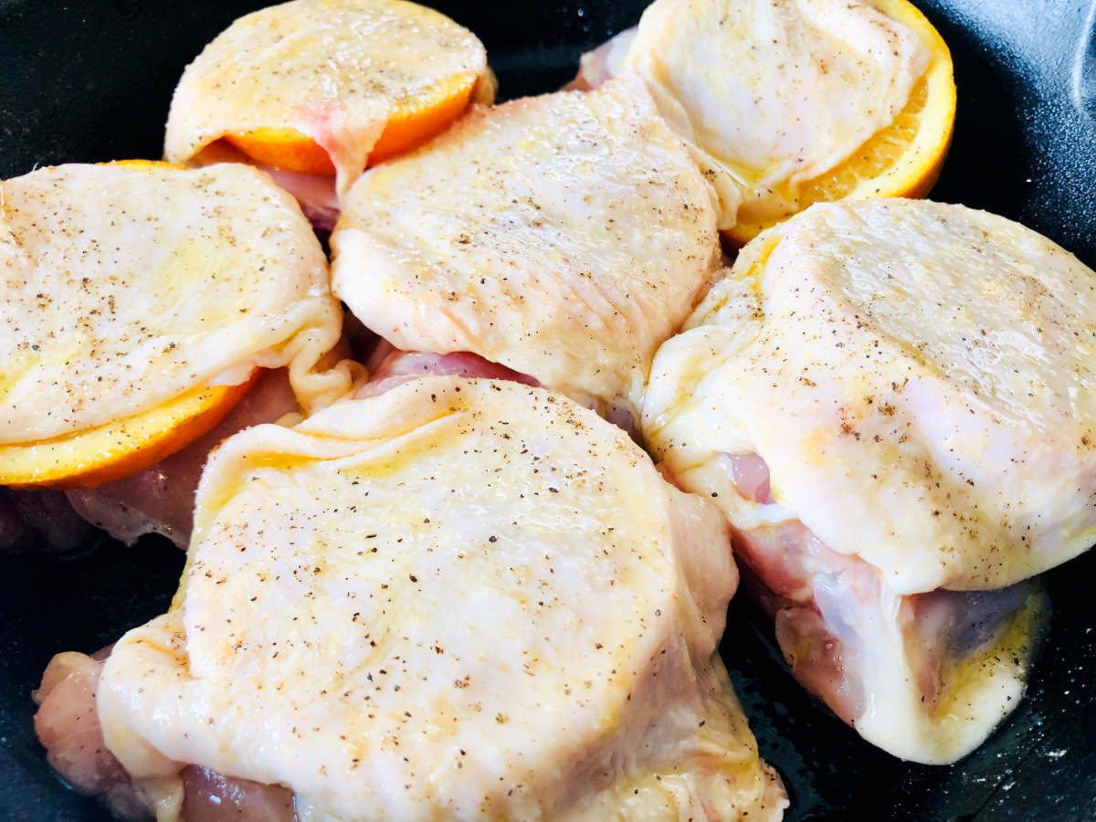 chicken thighs in pan with orange slices