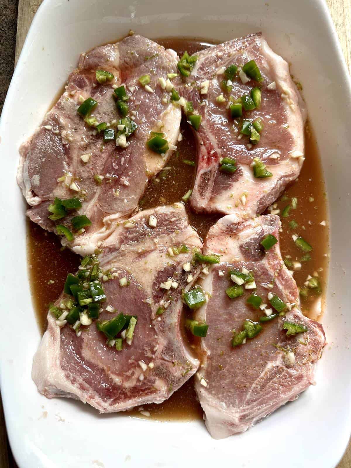 Pork chops in citrus ale marinade in dish. 