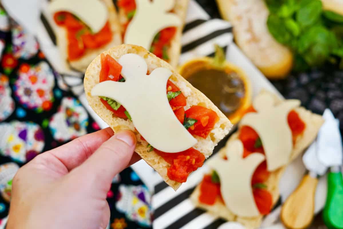 ghost shaped cheese over brushetta with hand holding