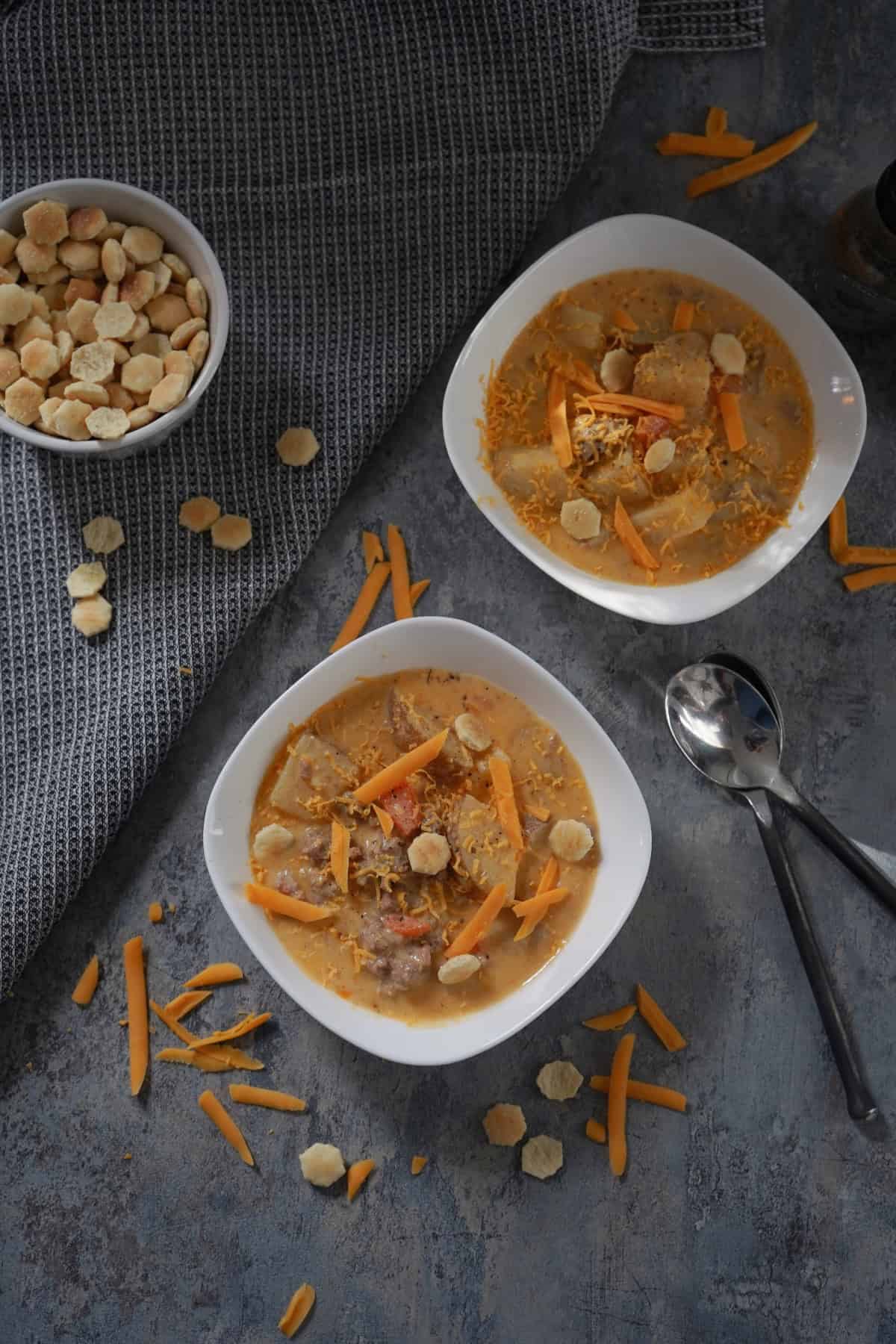 two bowl of soup with spoons and crackers 