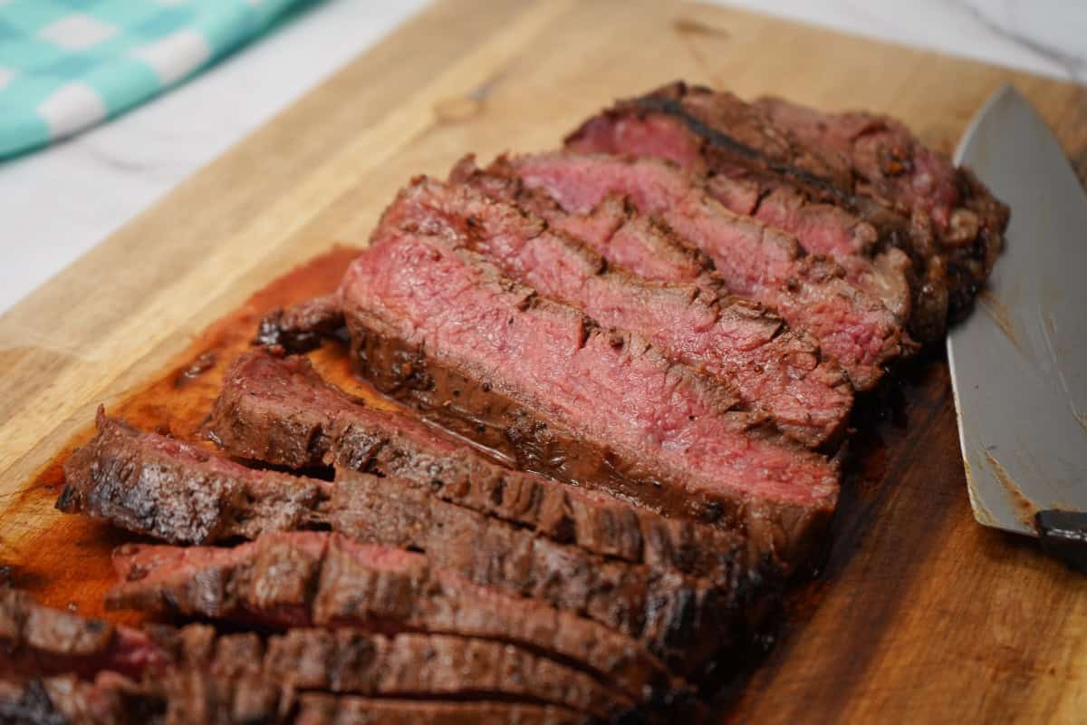 Marinated Flank Steak sliced with sharp knife behind it.