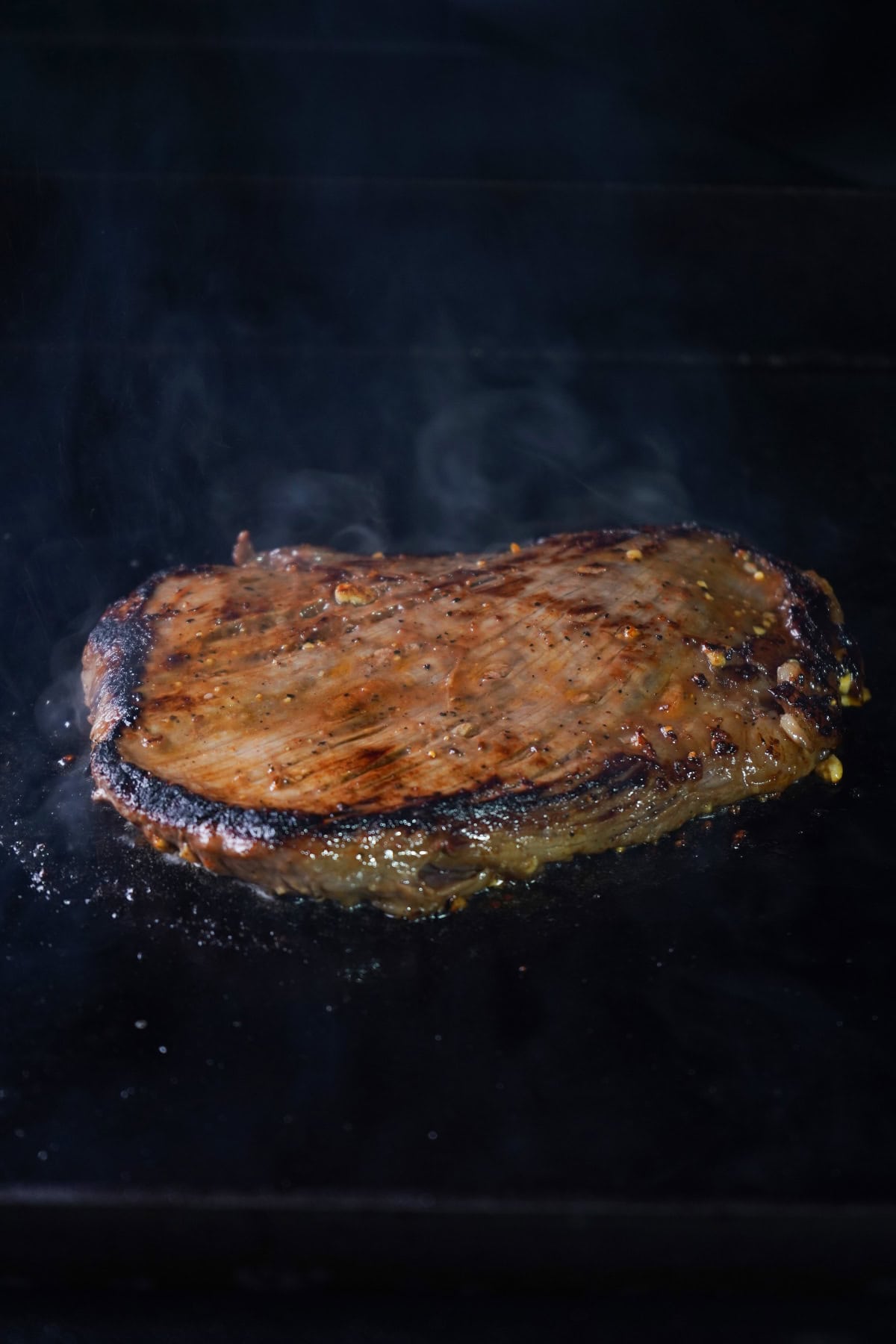 flank steak with crust bing seared on flat top