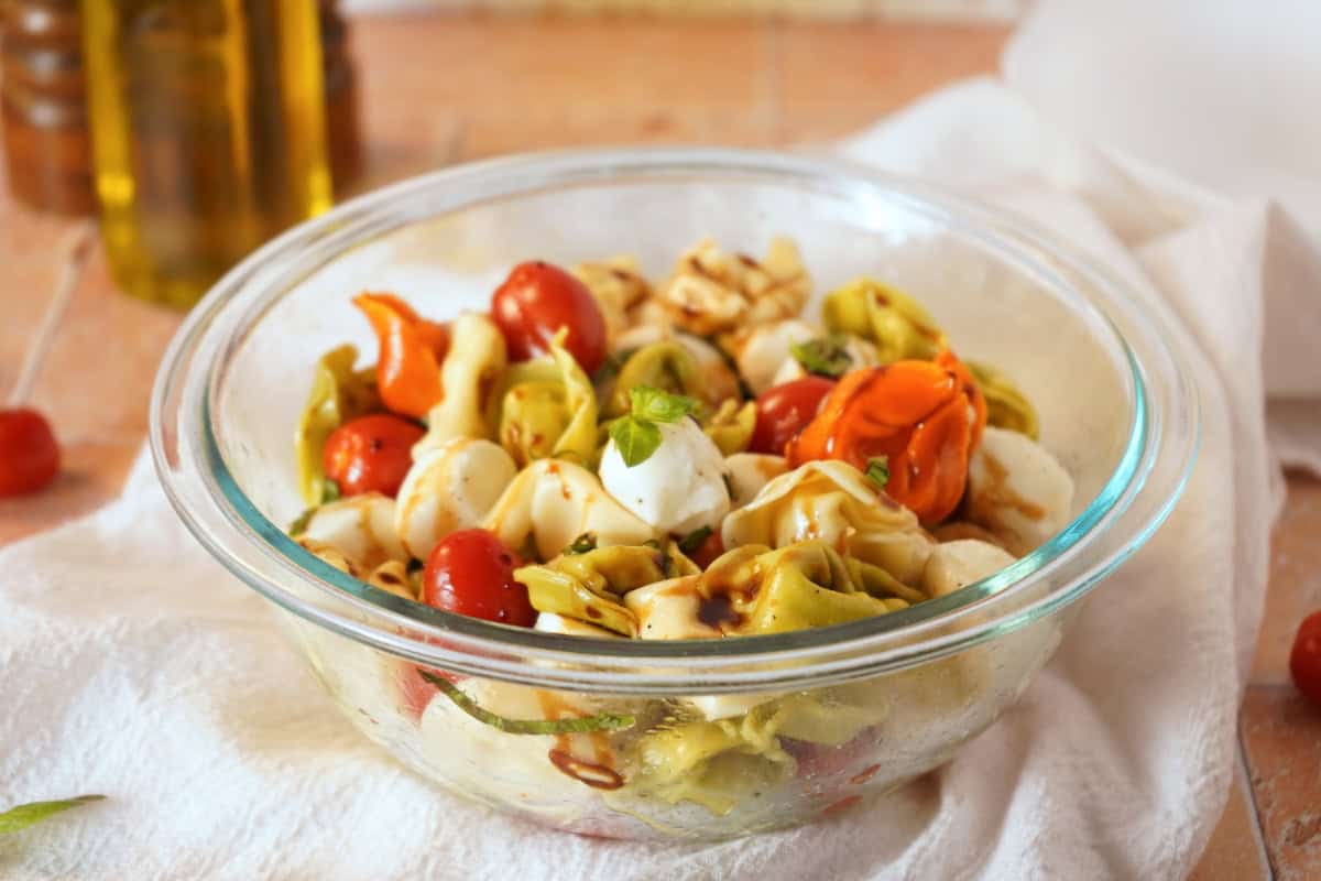 caprese pasta salad close up with olive oil in background