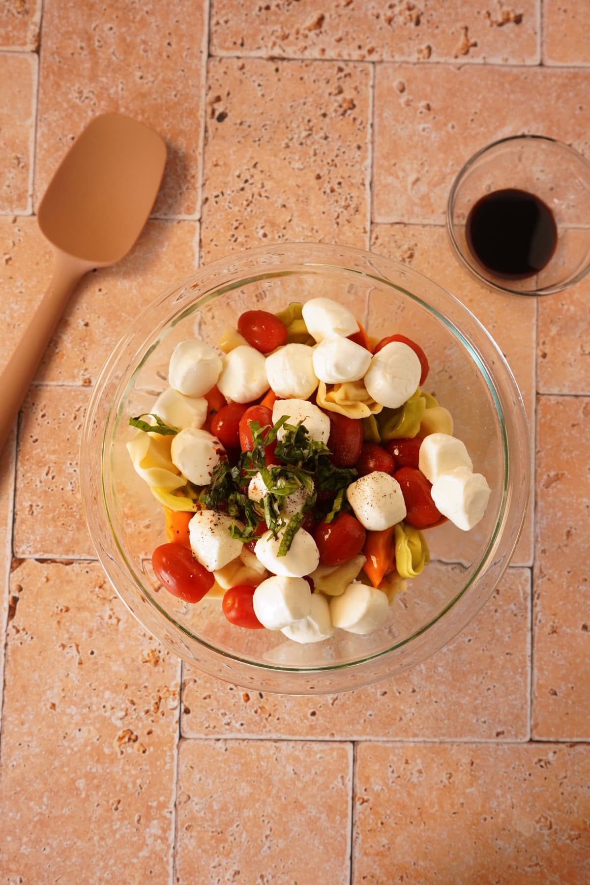 tortellini, tomatoes, mozzarella, and basil in glass bowl.