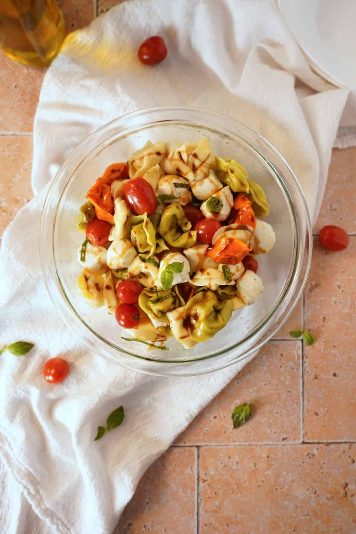 Tortellini pasta salad in bowl on white linen with balsamic glaze.