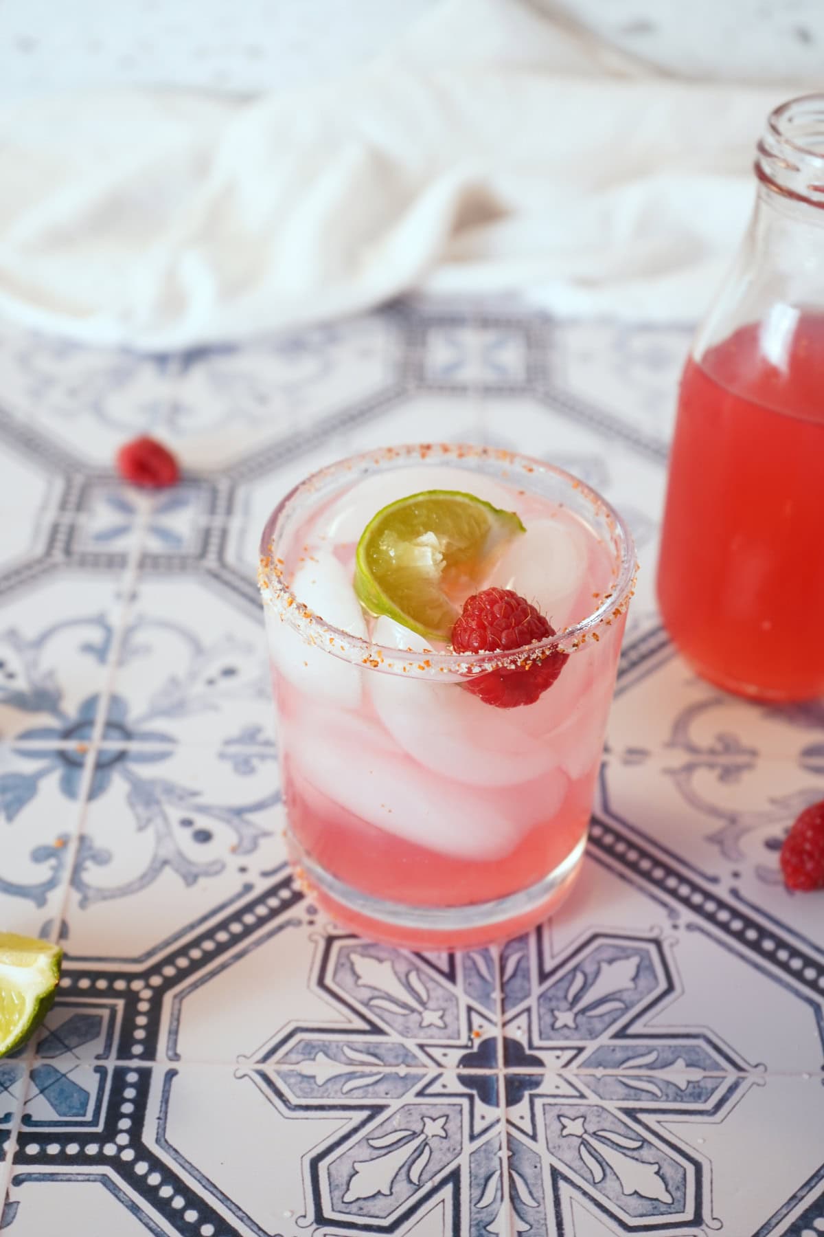 Raspberry lemonade margarita in glass with lime and raspberry on top.