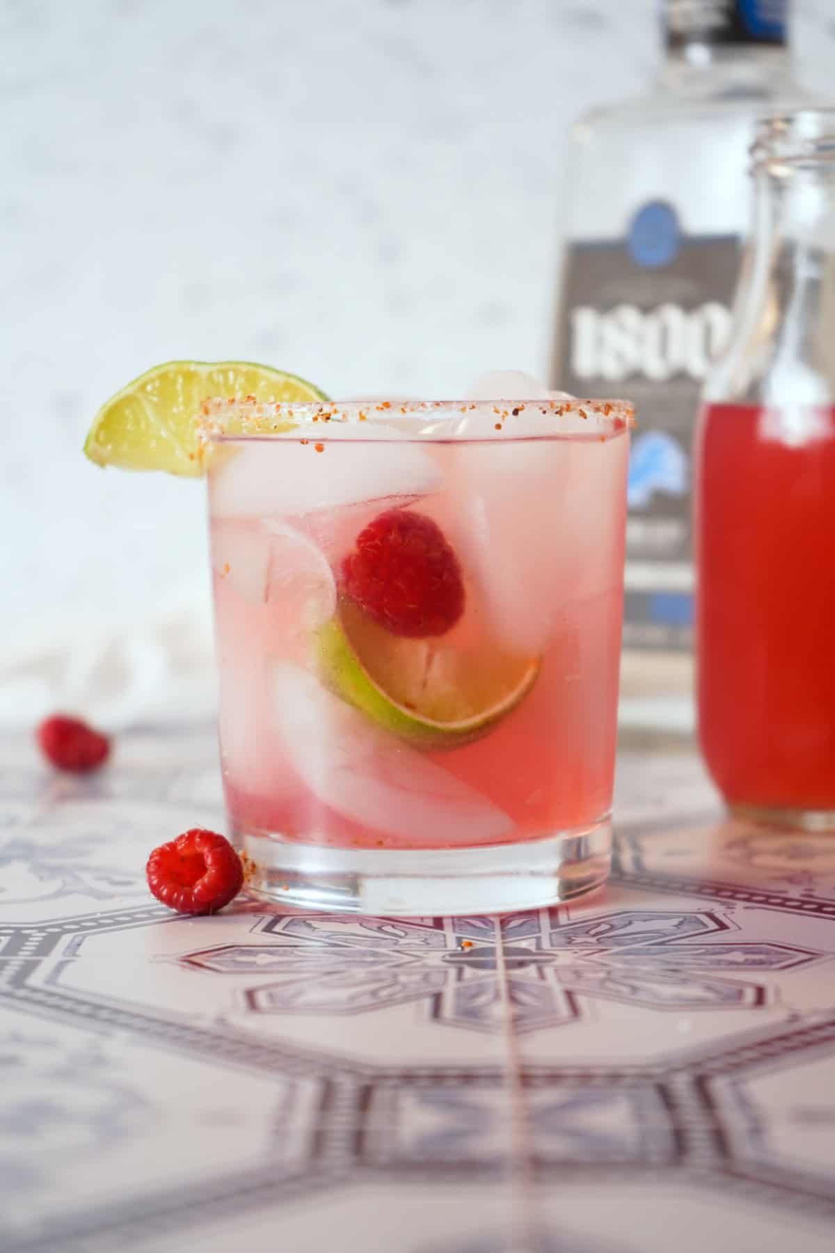 Raspberry margarita in glass garnished with lime and raspberries.