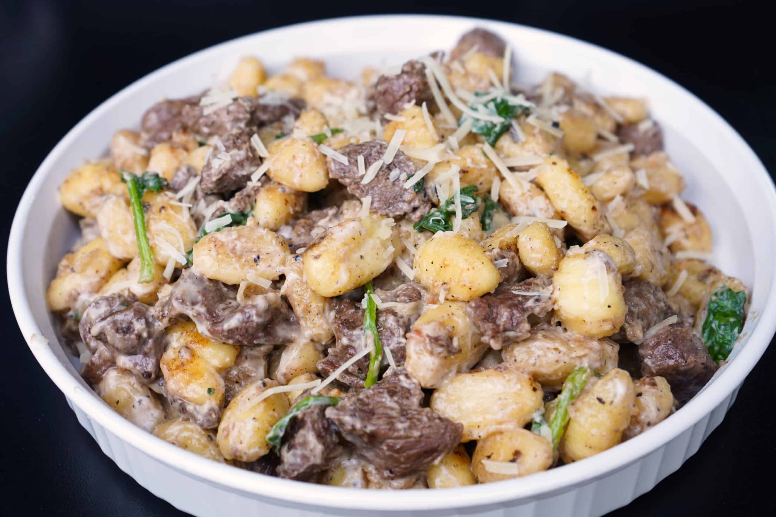 steak and gnocchi alfredo in white platter 