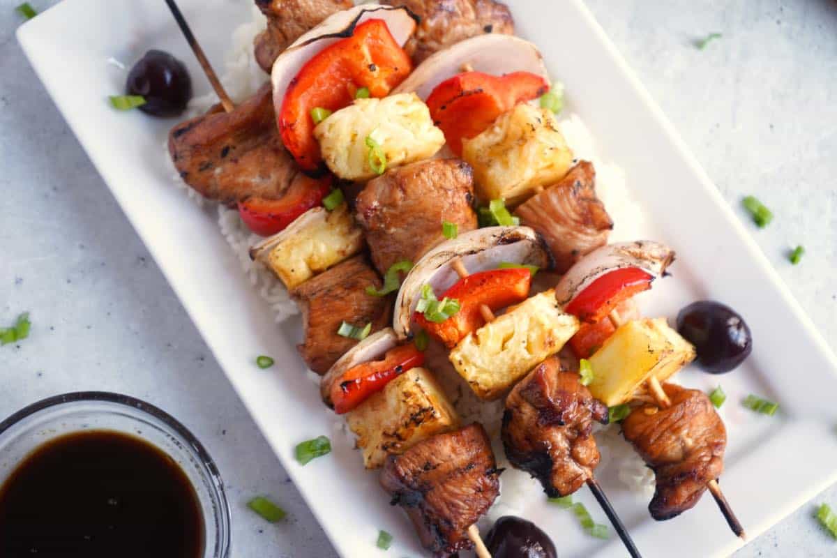 Cherry Chicken Skewers on white plate over rice.