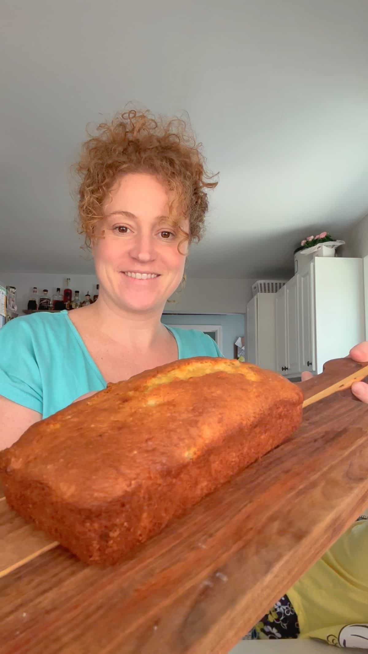 Me holding banana bread on cutting board 