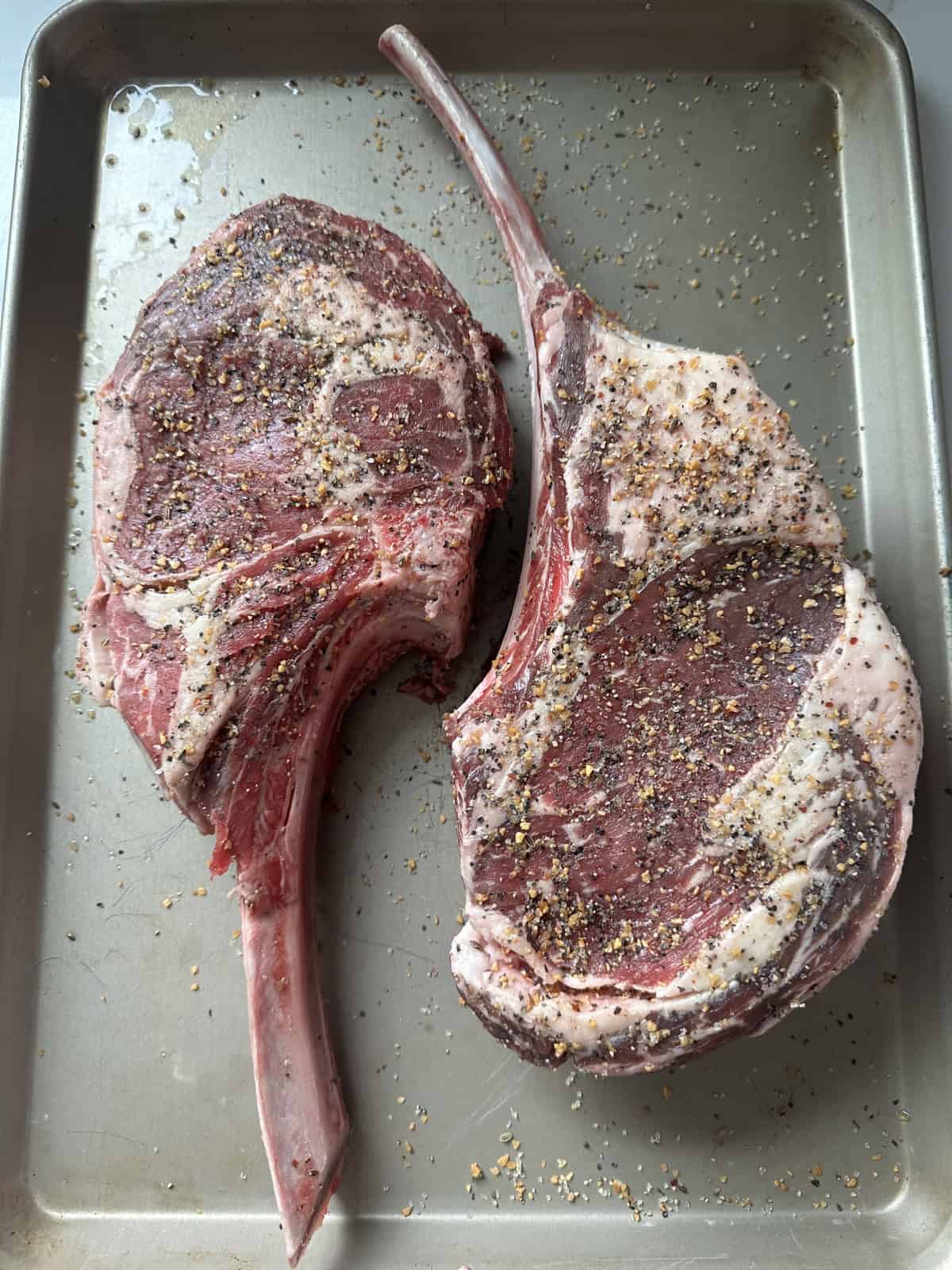 seasoned tomahawk steaks on baking sheet