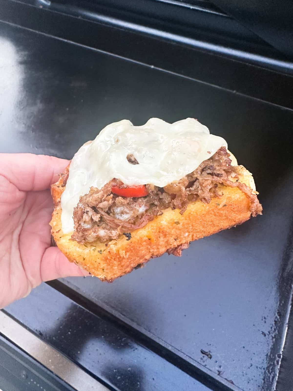 blackstone philly cheesesteak on texas toast in hand