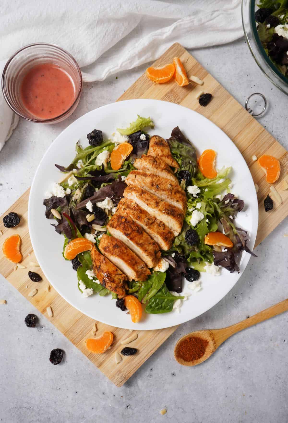 Blackened Chicken Salad one white plate with a dish of raspberry dressing.
