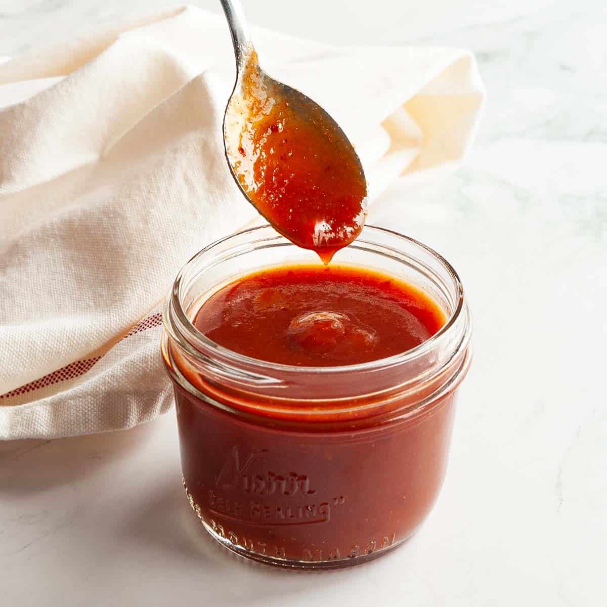 Spicy hot honey in a glass jar with a spoonful above.
