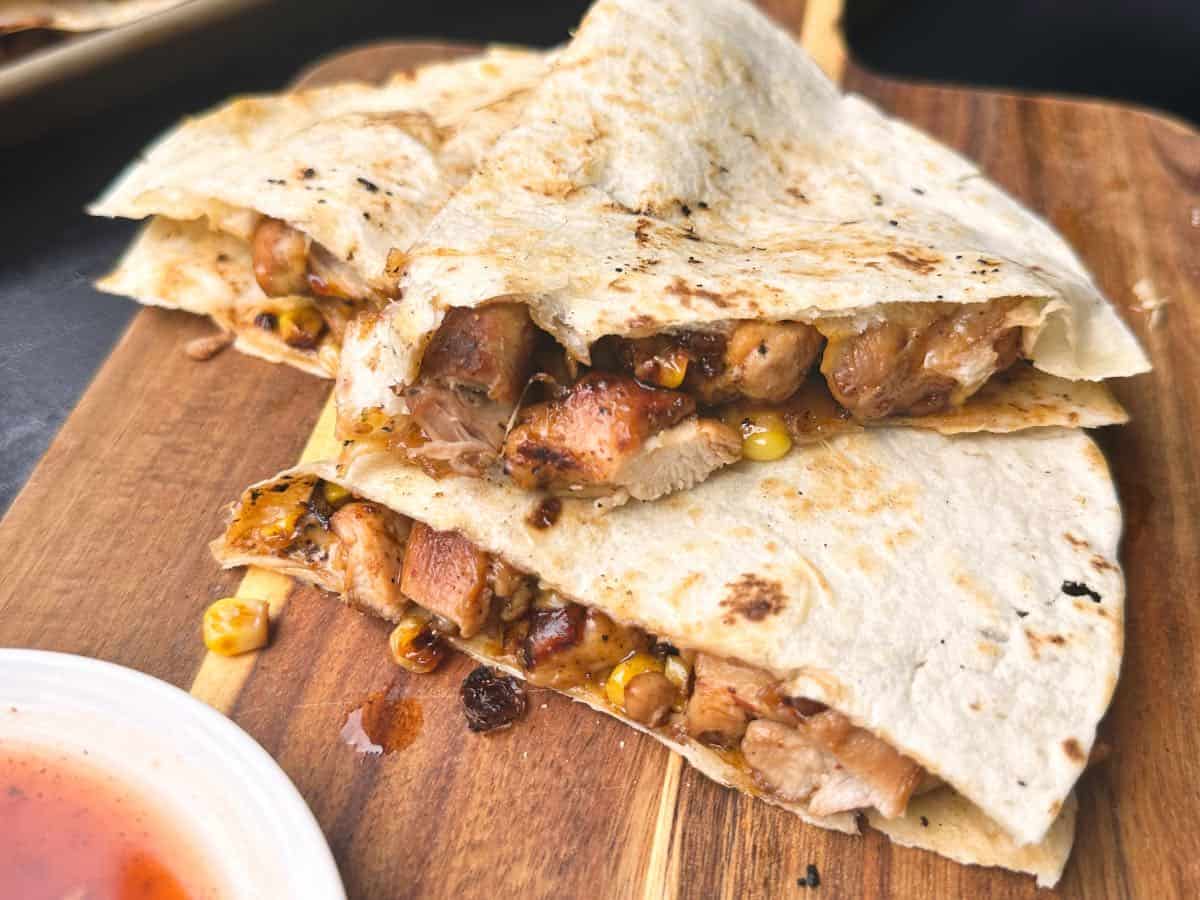 Two quesadillas stacked on cutting board. 