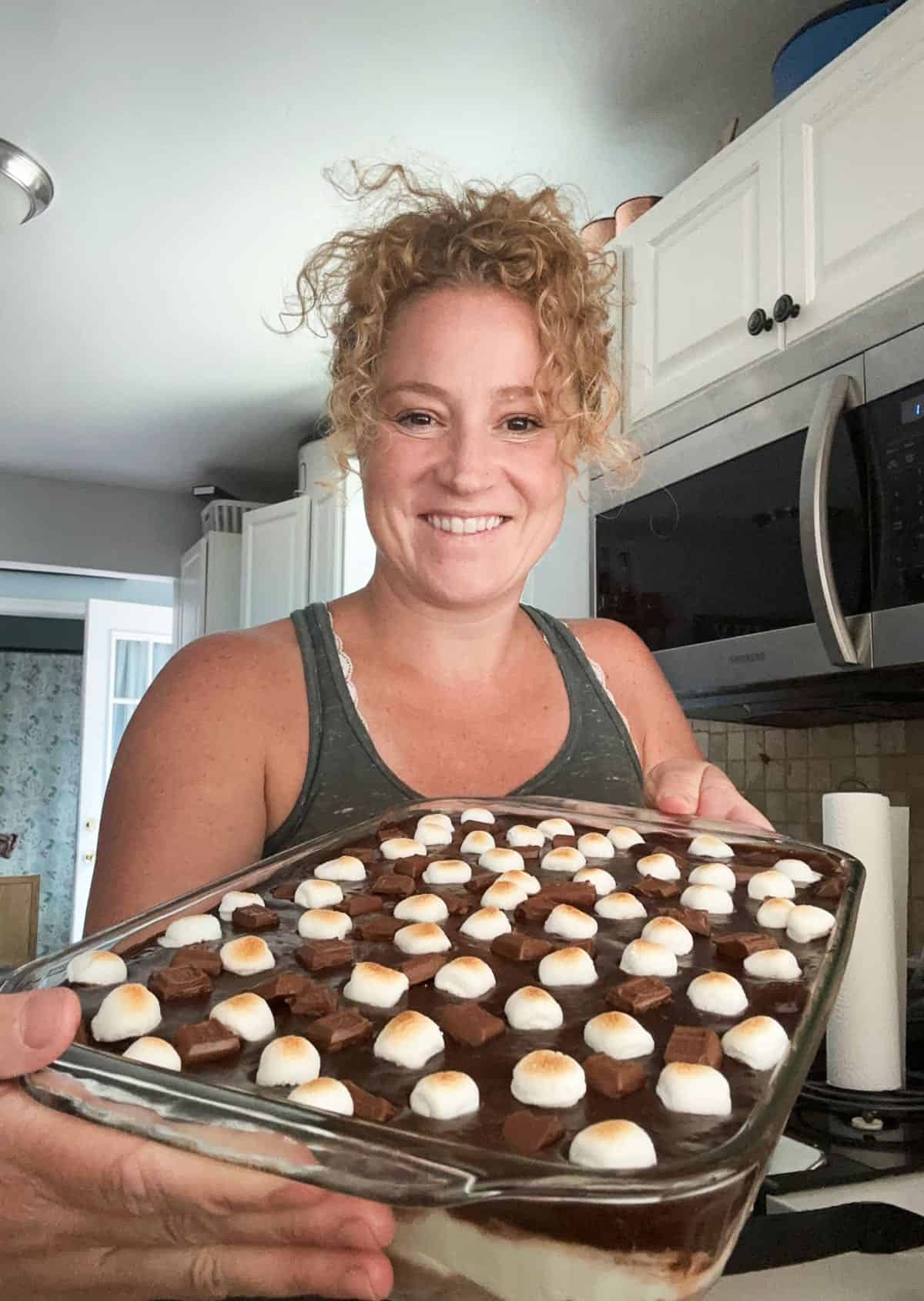 Stef holding the pan of s'mores eclair cake.